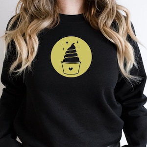 May include: Black sweatshirt with a yellow circle graphic of a swirl ice cream cone with a heart on the cup.