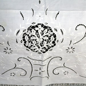 May include: White cotton fabric with intricate white embroidery in a floral pattern. The embroidery features a central circular design with delicate cutouts.