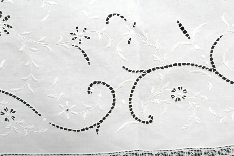 May include: White cotton fabric with a delicate embroidered design of black vines and flowers. The embroidery is done in a cutwork style, with the fabric removed to create the design.