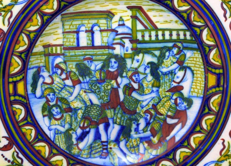 May include: A ceramic plate with a colorful scene of people in a medieval setting. The plate has a blue and white border with yellow and red accents.