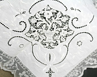 May include: White cotton fabric with intricate embroidered floral designs. The embroidery features delicate flowers and leaves, creating a classic and elegant pattern.