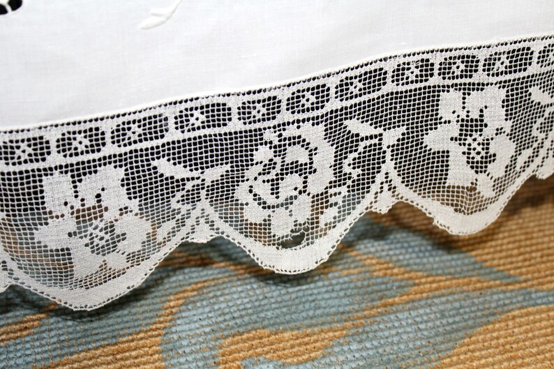 May include: White lace trim with a scalloped edge and a floral pattern. The lace is delicate and intricate, with a fine mesh design.