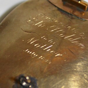 May include: A gold-toned oval brooch with an inscription that reads "Presented to Mrs. Golden for her many years of service".