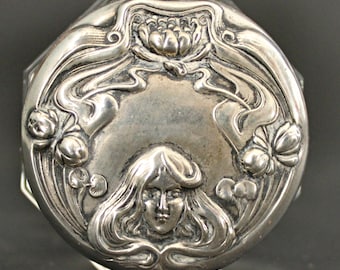 May include: A silver octagonal trinket box with an Art Nouveau design featuring a woman's face surrounded by stylized flowers and leaves.