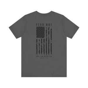 K&ouml;nnte beinhalten: Ein anthrazitfarbenes T-Shirt mit einem abgenutzten amerikanischen Flaggen-Design und dem Text "FEAR NOT FOR I AM WITH YOU, ISAIAH 41:10".