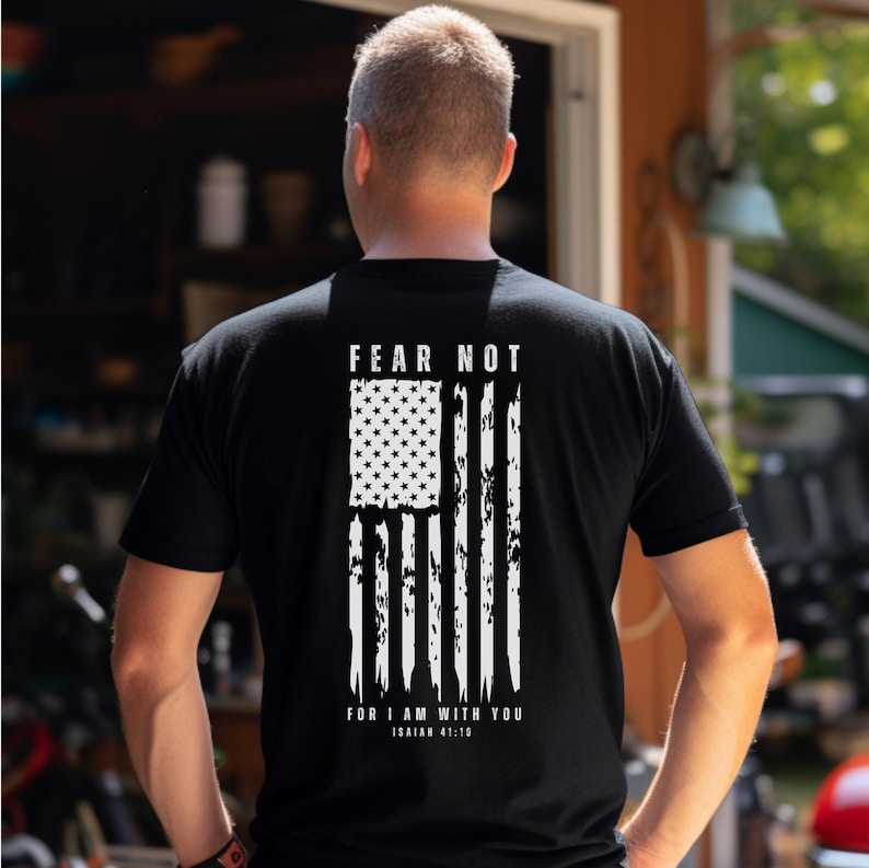 K&ouml;nnte beinhalten: Schwarzes T-Shirt mit einem wei&szlig;en, abgenutzten Design einer amerikanischen Flagge und dem Text "F&uuml;rchte dich nicht, denn ich bin bei dir, Jesaja 41:10".