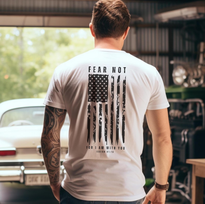 K&ouml;nnte beinhalten: Wei&szlig;es T-Shirt mit einem abgenutzten amerikanischen Flaggen-Design und dem Text "F&uuml;rchte dich nicht, denn ich bin mit dir, Jesaja 41:10".