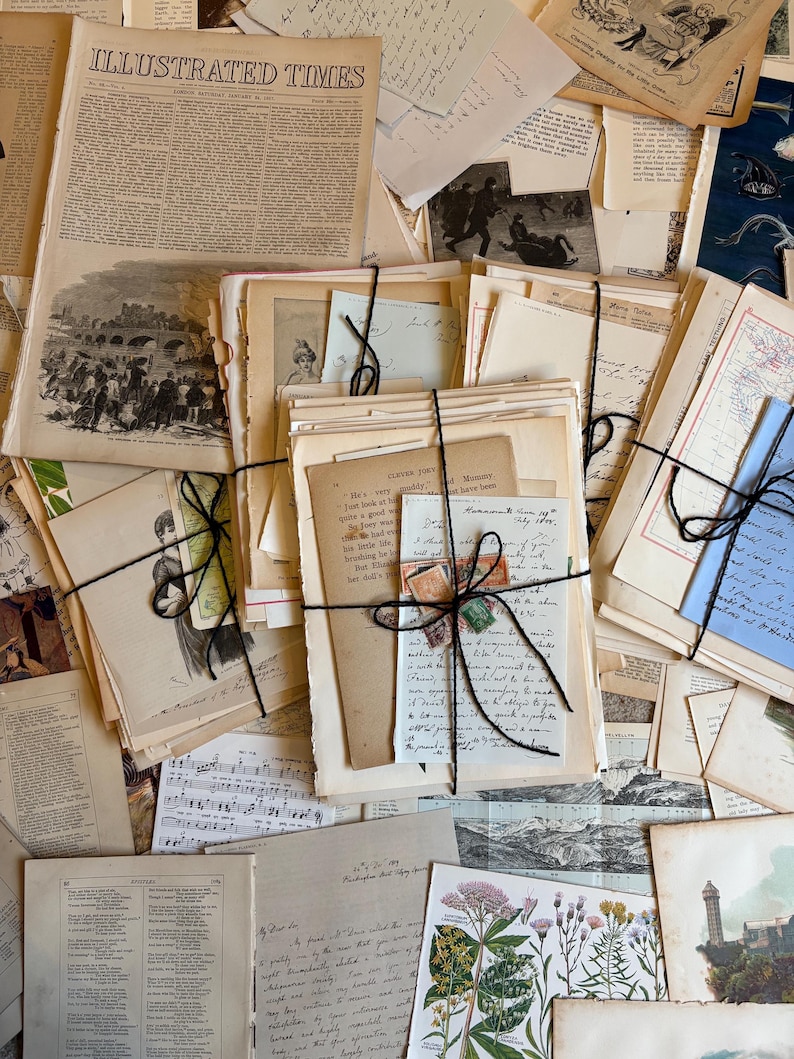 Bundle of over 100 vintage and antique paper ephemera pieces, including aged letters, postcards, and documents, arranged in a flat lay on a rustic wooden surface ready for scrapbooking and paper craft projects