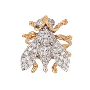May include: A gold and silver ring featuring a detailed bee design with a diamond-encrusted body and wings.