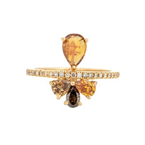 May include: A gold ring with a pear-shaped brown diamond in the center and smaller brown diamonds on the band. The band is set with smaller white diamonds.