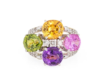 May include: A gold ring featuring four oval-shaped gemstones. The ring has a large, bright yellow centre stone, surrounded by a smaller green stone, a pink stone, and a purple stone. The ring is set with small diamonds.