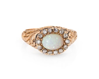 May include: A gold ring with an oval opal gemstone surrounded by a halo of small diamonds.