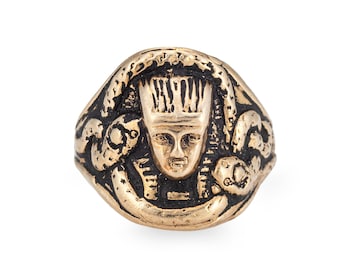 May include: A gold-toned ring with a detailed design of a pharaoh's head surrounded by snakes.