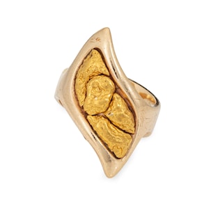 Puede incluir: Un anillo de oro con una gran pepita de oro irregular engastada en la banda. El anillo está hecho de oro de 14 quilates y tiene una forma única y orgánica.