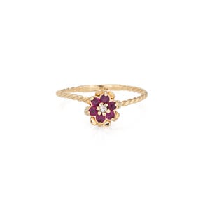 May include: A gold ring featuring a flower design. The flower has deep red petals and a small, central diamond. The band has a twisted rope design. The ring is set against a white background.