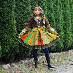 May include: A vibrant patchwork coat and skirt outfit. The coat is brown with colourful accents, and the skirt has vertical stripes of orange, green, and yellow. The ensemble is worn with black boots and blue jeans.