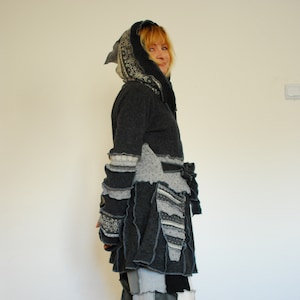 Könnte beinhalten: Eine Frau trägt eine graue Kapuzenjacke mit Patchwork-Muster und eine schwarze und weiße Patchwork-Hose.