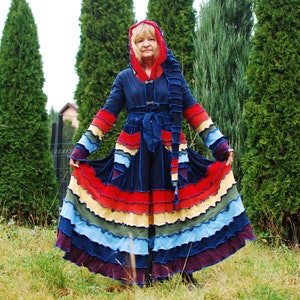 May include: A long, blue, hooded coat with a multi-coloured, ruffled skirt. The coat has a belt and is made from recycled materials.