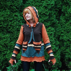 Könnte beinhalten: Ein brauner, orangefarbener und grüner Kapuzenpullover mit Patchwork-Design. Der Pullover hat eine Kapuze mit Kordelzug und lange Ärmel.