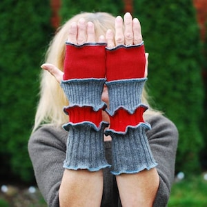 May include: A pair of fingerless gloves with red and gray stripes. The gloves are made of a soft, knitted fabric and have a ruffled edge.