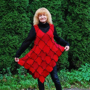 May include: A woman wearing a red, geometric patterned dress with a black turtleneck sweater and black pants.