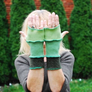 Puede incluir: Un par de guantes sin dedos verdes y negros con textura acanalada. Los guantes están hechos de un tejido suave y de punto.