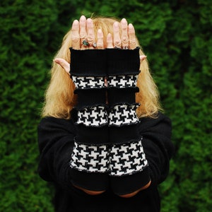 May include: Black and white houndstooth fingerless gloves with black cuffs. The gloves are folded over at the cuffs, creating a layered look.