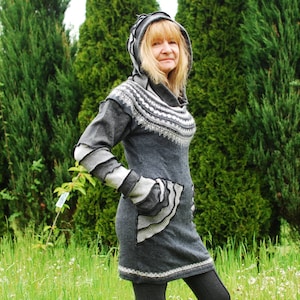 May include: A gray hooded sweater dress with a white and gray patterned design. The dress has a large pocket on the front and a ruffled hem.