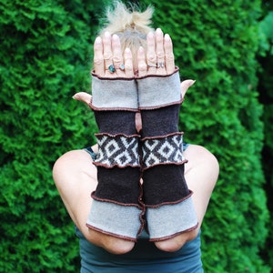 Könnte beinhalten: Ein Paar braune und graue Fingerlose Handschuhe mit geometrischem Muster. Die Handschuhe sind aus weichem, gestricktem Stoff und haben einen braunen Lederbesatz.
