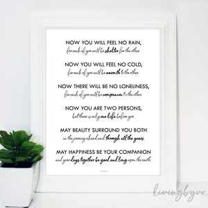 May include: A white framed print with a poem in black script. The poem starts with "Now you will feel no rain" and ends with "and your days together be good and long upon the earth." A small potted plant is positioned to the left.