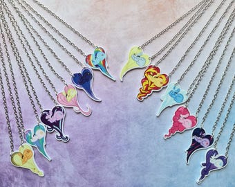 May include: A collection of silver-toned chain necklaces, each featuring a heart-shaped pendant. The pendants display colorful, stylized illustrations of cartoon ponies in various poses, with vibrant hues including rainbow, pink, blue, and purple.