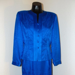 May include: A royal blue skirt suit with a button-up jacket and a matching skirt. The fabric has a subtle textured pattern.