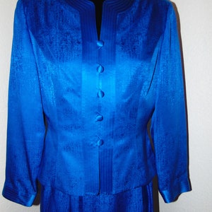 May include: A royal blue silk suit jacket and skirt with a satin finish and a row of buttons down the front.
