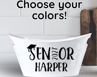 May include: A white oval plastic tub with a red interior rim. The front features black text that reads "SENIOR 2027 HARPER" with a graduation cap icon above the word "SENIOR". Above the tub, the text "Choose your colours!" is displayed.