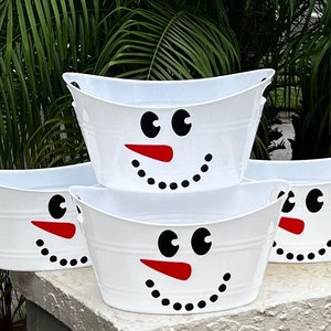 personalized christmas gift basket snowman bucket best seller trending christmas decor Snowman Face Holiday Basket Christmas Gift Basket Porch Decor Guest Bathroom Basket Holiday Tote Snowman Favor Bucket Personalized Basket May include: Three white metal tubs with snowman faces. The snowman faces have black eyes, red noses, and black dots for a mouth.