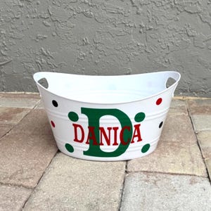 May include: White metal tub with handles, decorated with red, green, and black polka dots. The name "DANICA" is displayed in red letters with a green "D" on the front of the tub. A decorative item.