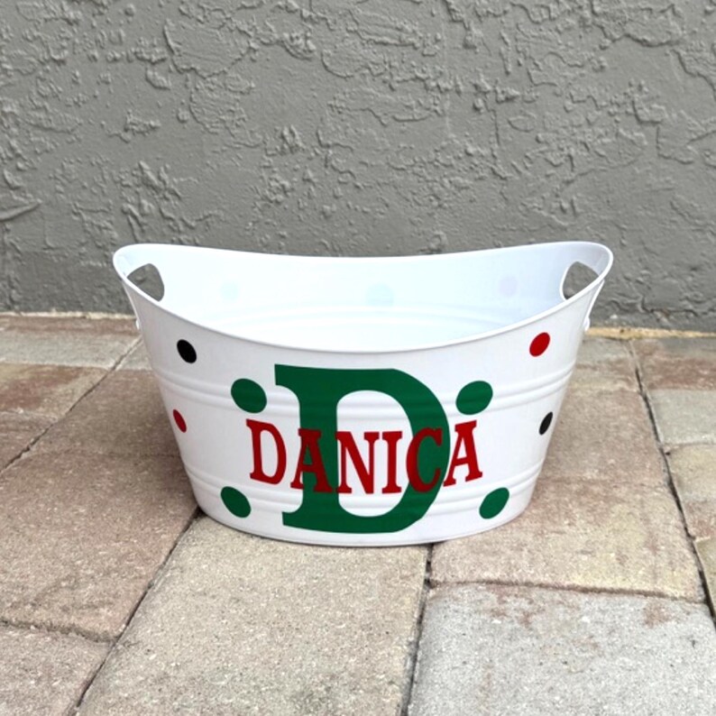 May include: White metal tub with handles, decorated with red, green, and black polka dots. The name "DANICA" is displayed in red letters with a green "D" on the front of the tub. A decorative item.