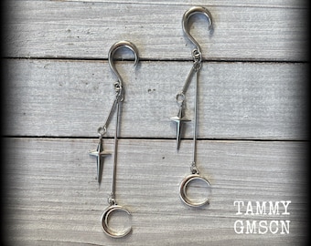May include: A pair of silver dangle earrings with a crescent moon and star charm. The earrings are made of surgical steel and are perfect for a gothic or celestial style.