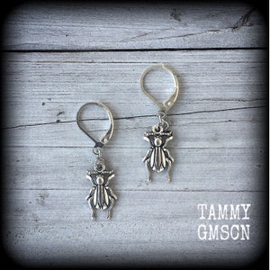 May include: A pair of silver earrings with a beetle charm hanging from each earring.