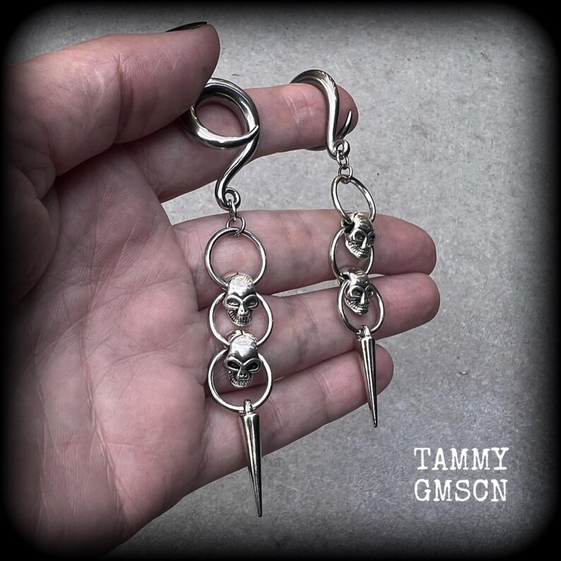 These awesome gauged earrings feature punk metal skull and spike dangles, are nice and lightweight, weighing 10 grams a piece, and nice and dangly at 10 cms from tip to tip.
This pair has been made on 2 gauge (6mm) surgical steel full curl hooks