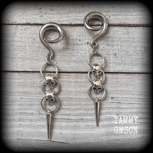 These awesome gauged earrings feature punk metal skull and spike dangles, are nice and lightweight, weighing 10 grams a piece, and nice and dangly at 10 cms from tip to tip.
This pair has been made on 2 gauge (6mm) surgical steel full curl hooks
