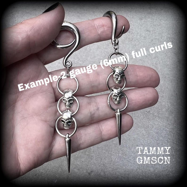 These awesome gauged earrings feature punk metal skull and spike dangles, are nice and lightweight, weighing 10 grams a piece, and nice and dangly at 10 cms from tip to tip.
This pair has been made on 2 gauge (6mm) surgical steel full curl hooks