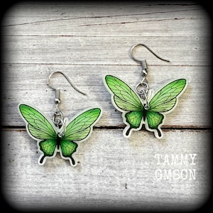 May include: A pair of green butterfly earrings with silver hooks. The butterflies have a translucent green color with darker green veins.