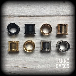 May include: Eight different ear gauges in various colors, including gold, silver, and black. The gauges are arranged in two rows of four.