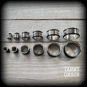 May include: A set of 10 silver ear gauges, ranging in size from small to large. The gauges are made of metal and have a smooth, polished finish.