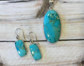 May include: A turquoise pendant necklace and matching earrings. The pendant is oval shaped and the earrings are rectangular. The jewelry is made of silver and turquoise.