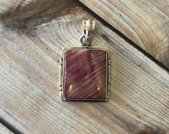 May include: A silver pendant with a rectangular pink and white stone set in a silver frame.