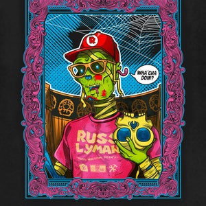 May include: Black t-shirt featuring a colorful graphic of a zombie character wearing a red cap and sunglasses, holding a skull. The graphic includes the text "RUS LYMAN" and a speech bubble saying "WHA' CHA DOIN?"
