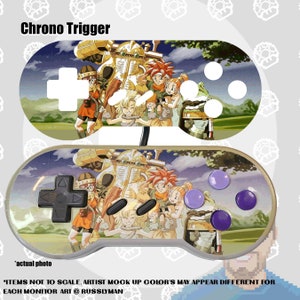 May include: A custom-designed video game controller featuring artwork from the game "Chrono Trigger." The controller has a colorful design with characters and scenes from the game. The text "Chrono Trigger" is at the top.