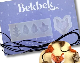 May include: A translucent silicone mold featuring four leaf shapes and one fox head shape, displayed on a purple card with the text Bekbek makes. A black cord necklace features orange fox and brown leaf pendants made from the mold.